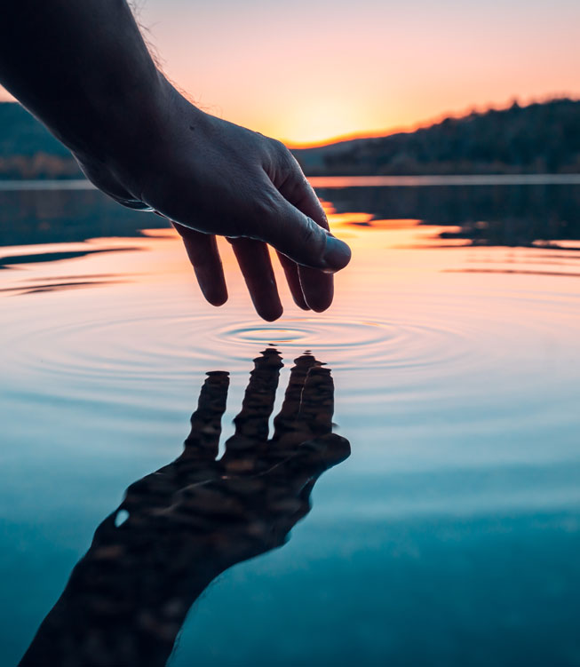 Finger touches surface of mountain lake